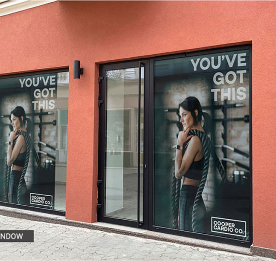 A woman stands in front of a store window, observing the displayed items with interest.