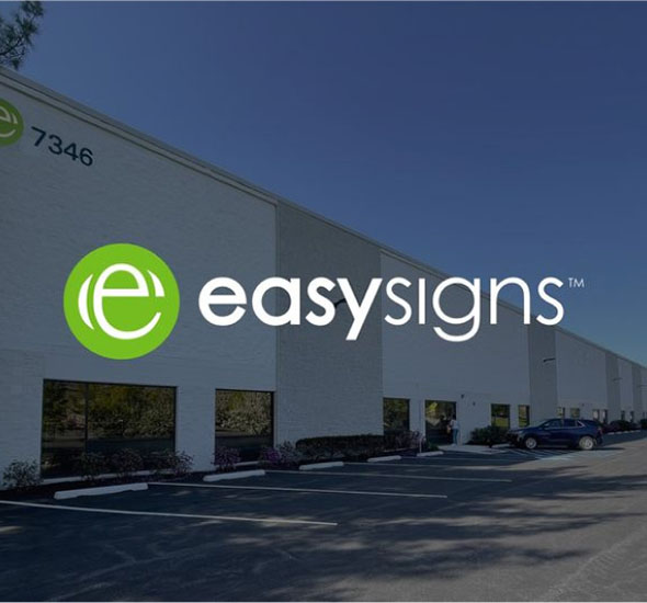 The Easy Signs logo displayed prominently on a building, with visible parking spaces in the foreground.