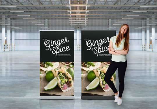 A woman stands beside a roll-up banner, showcasing a professional setting or event.