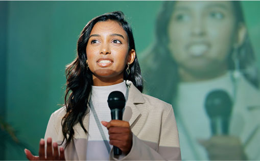 A woman confidently speaks into a microphone, engaging her audience with her voice and presence.