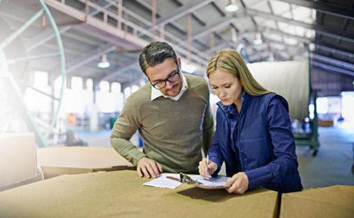 A man and woman reviewing documents together in a spacious warehouse environment.