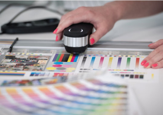 A person operates a color printer, producing a vibrant color chart for reference or design purposes.