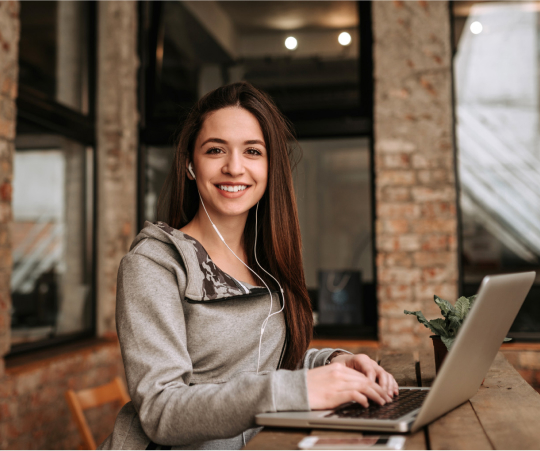 A woman smiles while working on her laptop, showcasing a moment of joy and productivity.