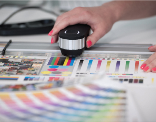 A person operates a laser printer, producing a vibrant color chart for analysis or design purposes.