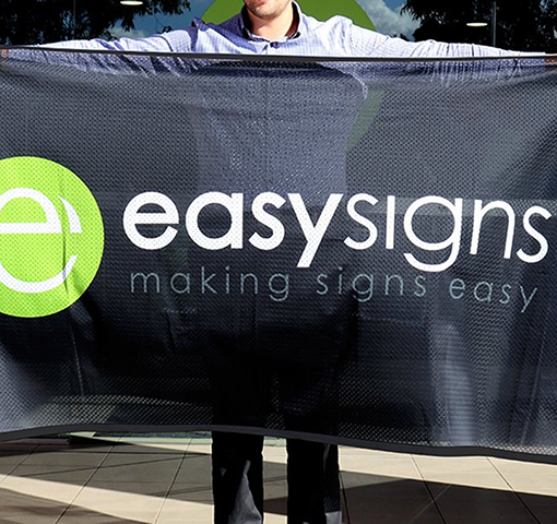 A man stands holding a sign that reads 'Easy Signs', conveying a message of simplicity and clarity in communication.