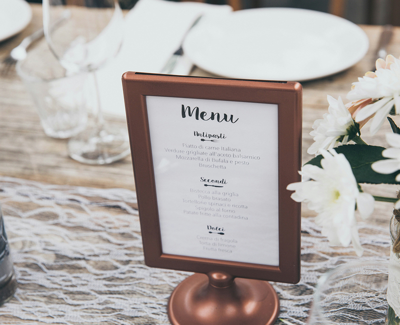 Wedding menu elegantly displayed on a rustic wooden table, showcasing a charming and intimate dining setting.