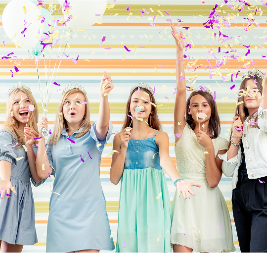 Five young women joyfully holding colorful balloons and confetti, celebrating a festive occasion together.