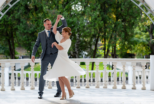 A bride and groom share a romantic dance beneath a beautifully decorated archway, surrounded by an enchanting atmosphere.