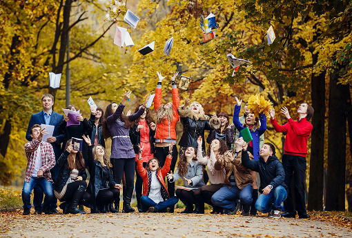 A group of individuals smiling together for a photo amidst colorful autumn foliage.