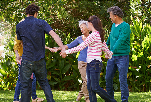 A diverse group of individuals standing in a park, holding hands in unity and friendship.