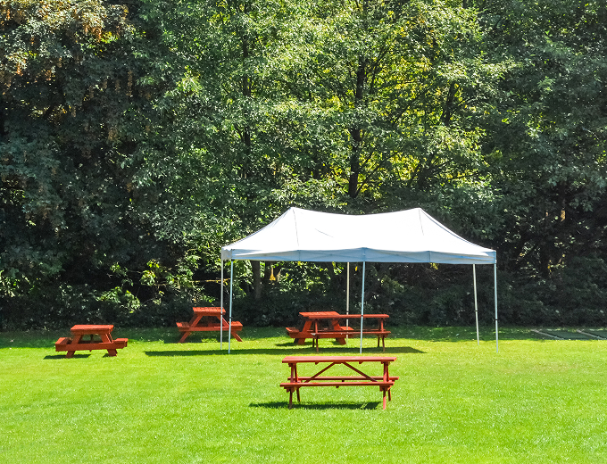 A picnic table and a tent set up in a lush grassy field, inviting for outdoor gatherings and relaxation.