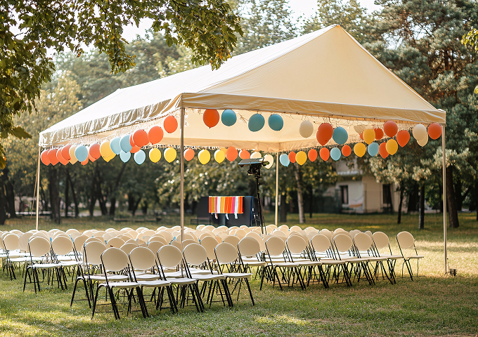 A tent adorned with chairs and colorful balloons, creating a festive outdoor gathering space.