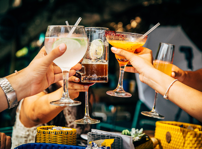 A diverse group of people raising their drinks in a toast, smiling and celebrating together in a joyful atmosphere.