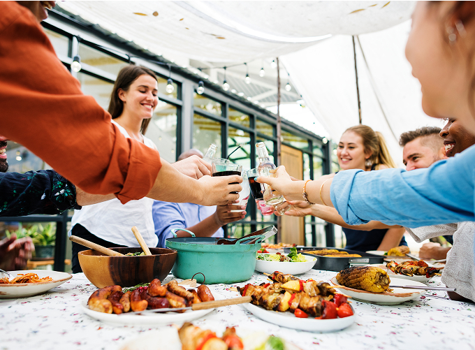 A group of diverse individuals raising glasses in a toast around a beautifully set dinner table.