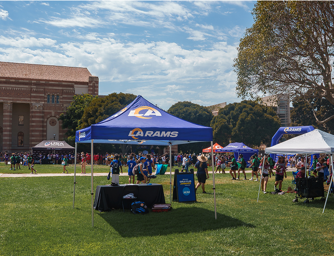 A large group of people gathered and seated under a tent, engaged in conversation and enjoying the event.