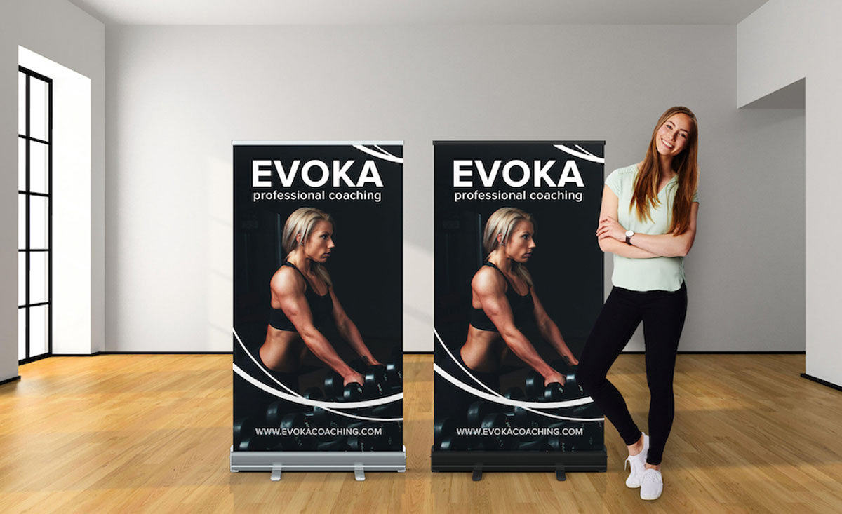 A woman stands beside two roll-up banners, showcasing informative graphics in a professional setting.