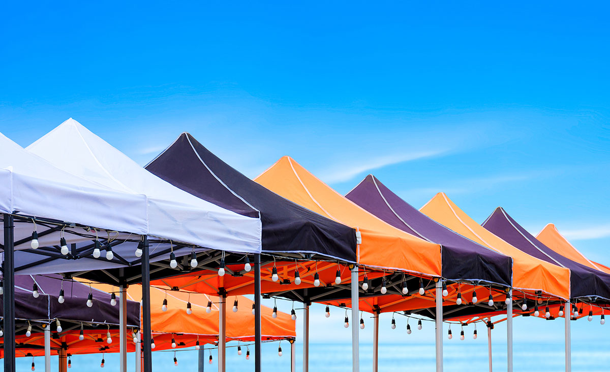 A row of tents featuring vibrant orange and black stripes, set against a clear background.